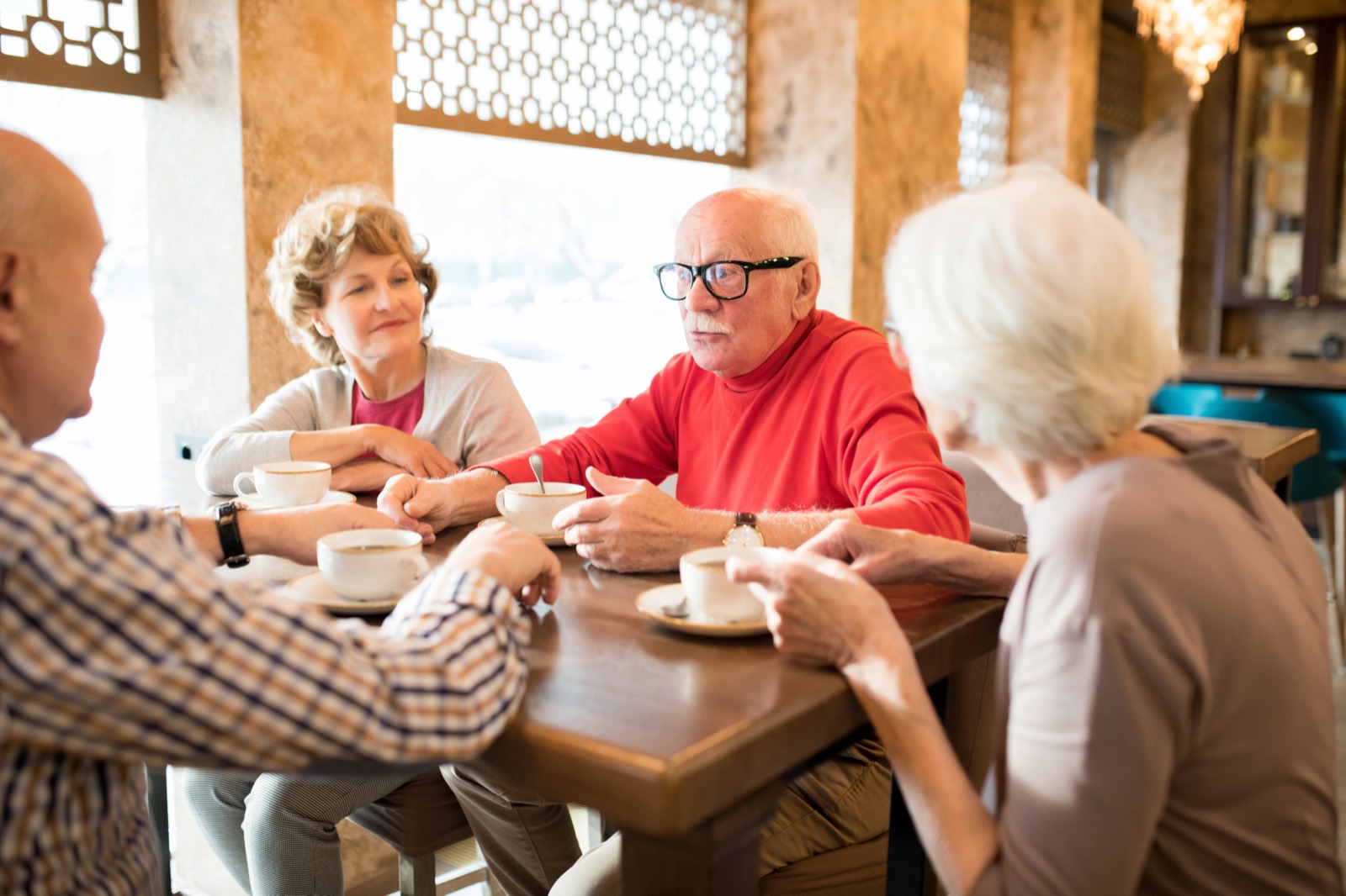 Four friends talking over coffee at a cafe table