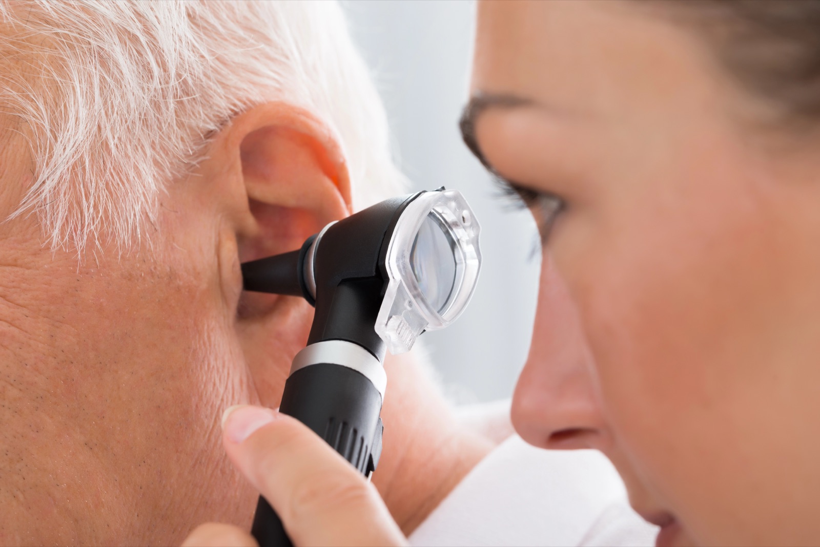 A clinician looking into a patient's ear with an otoscope
